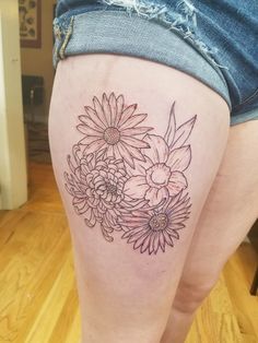 a woman's thigh with flowers tattooed on the side and her lower leg in black ink