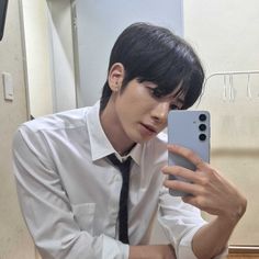 a man in a white shirt and tie taking a selfie with his cell phone