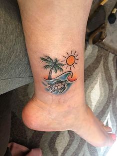 a small foot tattoo with a turtle and palm tree on the beach in the background