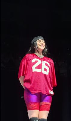 a woman in red jersey and purple shorts on stage