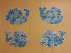 two pieces of paper cut out to look like blue fish on yellow wood paneled wall