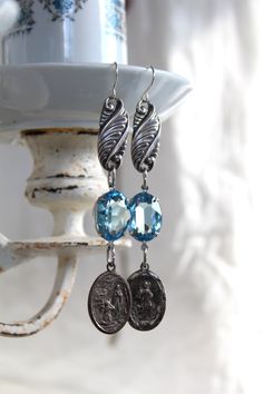 "This beautiful pair of earrings make a lovely statement from top to bottom. The top connector pieces are links from an antique sterling silver bracelet. From them, dangle two beautifully clear and crisp light blue swarovski crystals. From those , are two devotional medals. One medal says St. Bernadette, with an image of Bernadette at the grotto with the apparition of Mary, and the other says \"Our Lady of Mt. Carmel, pray for us.\" These earrings are about 3 1/4\" long without the earwires. Old Our Lady Of Mt Carmel, Medal Jewelry, St Bernadette, Assemblage Earrings, Vintage Assemblage Jewelry, Found Object Jewelry, Vintage Inspired Earrings, Vintage Assemblage, Assemblage Necklace