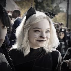 two women with cat ears and black cats on their heads are standing next to each other