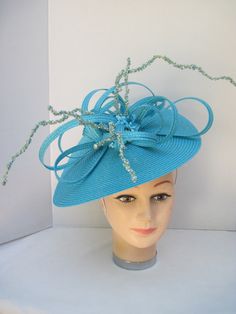 "* This design can be worn on either side of the head and has a sophisticated side tilt. It features a monocromatic color scheme in a tantalizing turquoise. The center of the hat form has a burst of looped and swirled braiding accented by enhanced clusters of matching berries and curly berry twigs. * On an 12\" round flat hat form this is a great design for spring and summer and will also go right into the fall and winter as well. * It is light weight, balanced and comfortable on a white satin c Blue Fitted Fascinator For Beach, Turquoise Fitted Hat With Curved Brim, Fitted Turquoise Hat With Curved Brim, Elegant Turquoise Headpiece For Wedding, Elegant Turquoise Wedding Headpiece, Elegant Turquoise Fascinator For Races, Elegant Turquoise Fascinator For Wedding, Fitted Turquoise Summer Hat, Turquoise Fitted Summer Hat