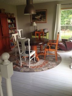 a dining room table and chairs in front of a large window with an area rug on the floor