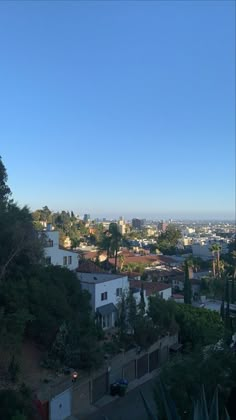 a view of the city from atop a hill with trees and buildings in the foreground