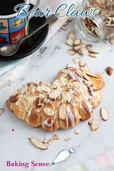 a close up of a pastry on a table with almonds and a cup of coffee