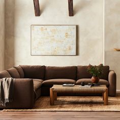 a living room with a brown couch and coffee table in front of a painting on the wall