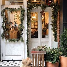 a store front with potted plants on the outside and an open door to it