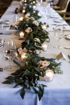 a long table with candles and greenery on the top is set for an event