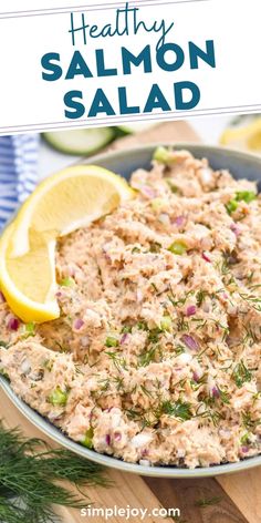 salmon salad in a bowl with lemon wedges and dill garnish on the side