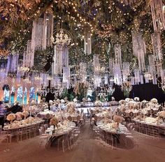 a large room filled with lots of tables covered in white flowers and chandeliers