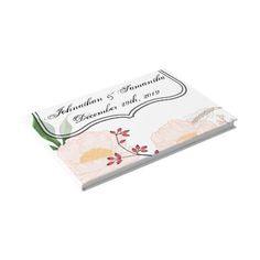 a wedding guest book with flowers and leaves on the front, in white paper cover