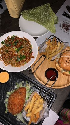 three plates of food are sitting on the table next to each other, including fries and burgers