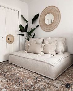 a living room with a couch, mirror and potted plant