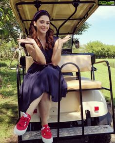 a woman is sitting in the back of a golf cart with her legs crossed and red shoes on