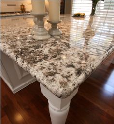 a marble counter top in a kitchen next to a candle holder on a wooden floor