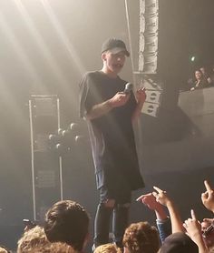 a man standing on top of a stage holding a microphone in front of a crowd