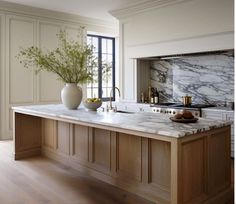 a large kitchen with marble counter tops and wooden cabinets in the center, along with a vase filled with flowers