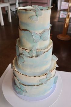 a three tiered cake with blue butterflies on it