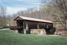 a covered bridge over a river in the woods