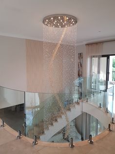 a spiral staircase with glass railings and chandelier hanging from it's ceiling