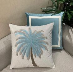 two pillows sitting on top of a couch next to a plant