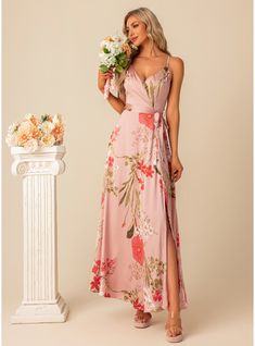 a woman standing next to a white vase with flowers in it and wearing a pink floral print dress