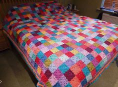 a multicolored crocheted blanket on a bed