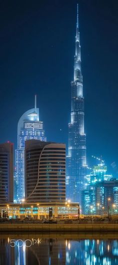 the city skyline is lit up at night with skyscrapers and buildings reflected in the water