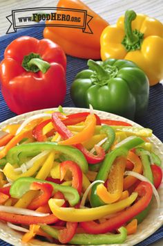 colorful peppers on a white plate next to other vegetables