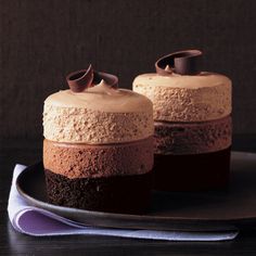 two cakes with chocolate frosting and decorations on top are sitting on a black plate