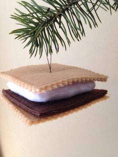 a christmas ornament hanging from a tree branch with two pieces of felt on it