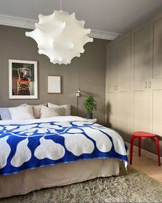 a bedroom with a bed, chair and pictures on the wall above it that is decorated in blue and white