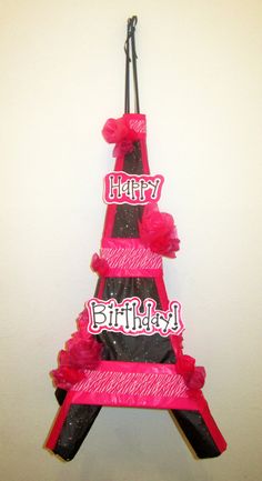 a pink and black birthday cake with the eiffel tower on it's side