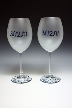 two wine glasses with numbers on them sitting side by side in front of a black background