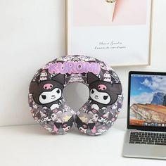 a laptop computer sitting on top of a desk next to a donut shaped pillow