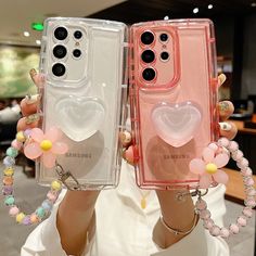 two people holding up cell phones with hearts on them