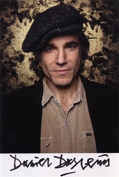 a man wearing a black hat standing in front of a grungy wall and looking at the camera