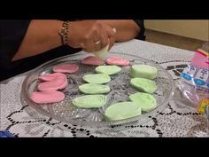 a person is decorating some cookies on a glass plate with pink and green frosting