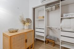 a bedroom with white walls and wooden floors, an open closet is next to the bed