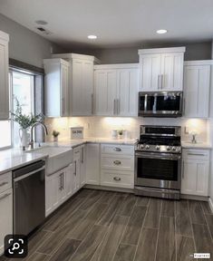 an empty kitchen with white cabinets and stainless steel appliances in the center, along with wood flooring