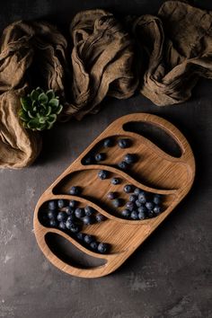 a wooden tray filled with blueberries on top of a table next to some cloth