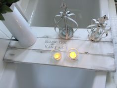 two candles are lit in front of a bathtub with the word shabby chic written on it