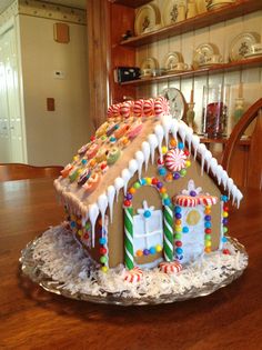 a gingerbread house with icing and candy on it sitting on a glass plate