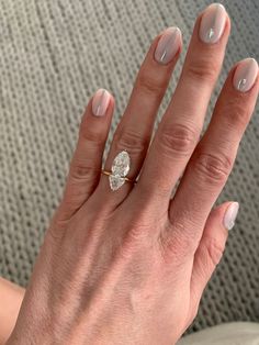 a woman's hand with a diamond ring on her left hand, sitting on a couch