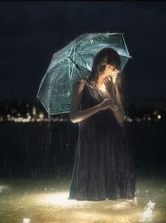 a woman standing in the rain holding an umbrella