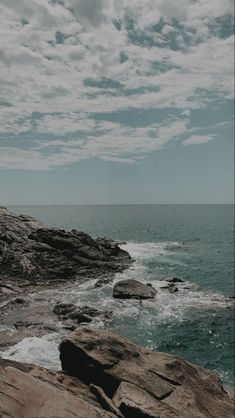 an ocean view with rocks and water under a cloudy sky