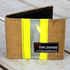 a wallet sitting on top of a wooden table next to a card holder with a yellow stripe