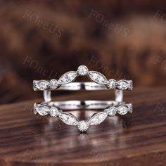 the wedding ring is made with white gold and diamonds, set on top of a wooden table